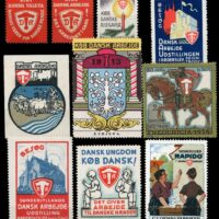 DA – Dansk Arbejde = Danish Work. The shield with a hammer and the letters DA appear on many Danish poster stamps and in advertisements. Landsforeningen Dansk Arbejde was founded in 1908 to promote Danish-made products for domestic purchase and export.